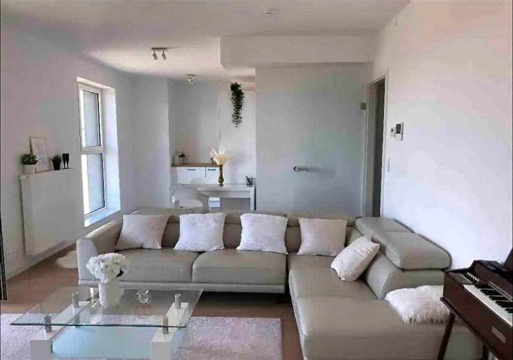 un soggiorno con divano e tavolo in vetro di Paradis Express - Guillemins Luxury apartment a Liegi