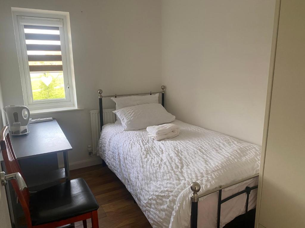 Foleshill的住宿－C.K. APARTMENT，一间卧室配有一张床、一张书桌和一个窗户。