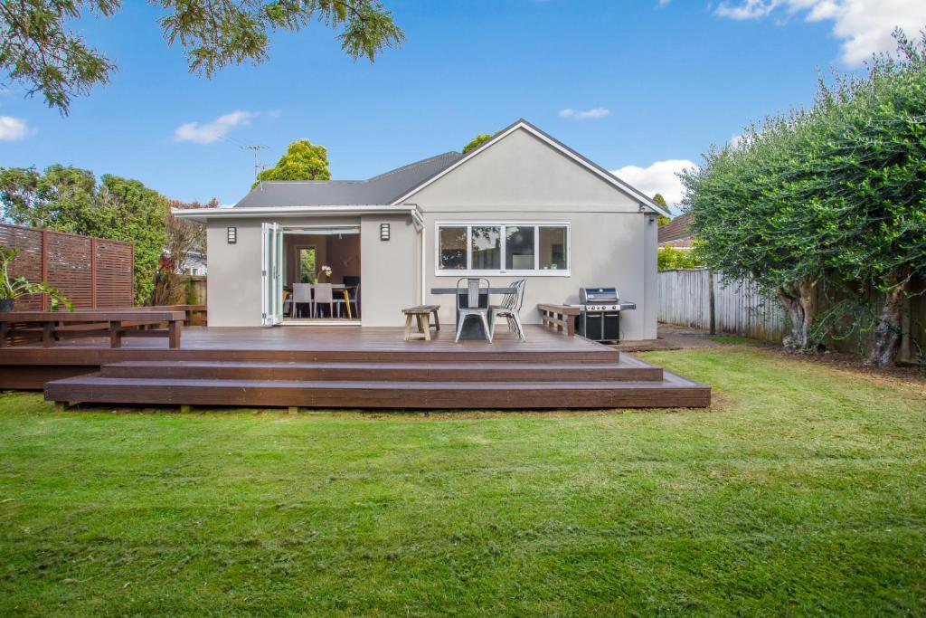 a small white house with a patio and a yard at Prosper Point Home with BBQ, Patio and Parking in Auckland