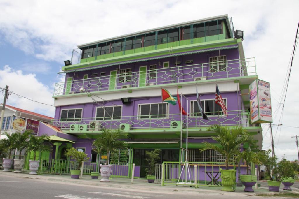 a purple and green building with palm trees in front of it at PG Quality Inn in Georgetown