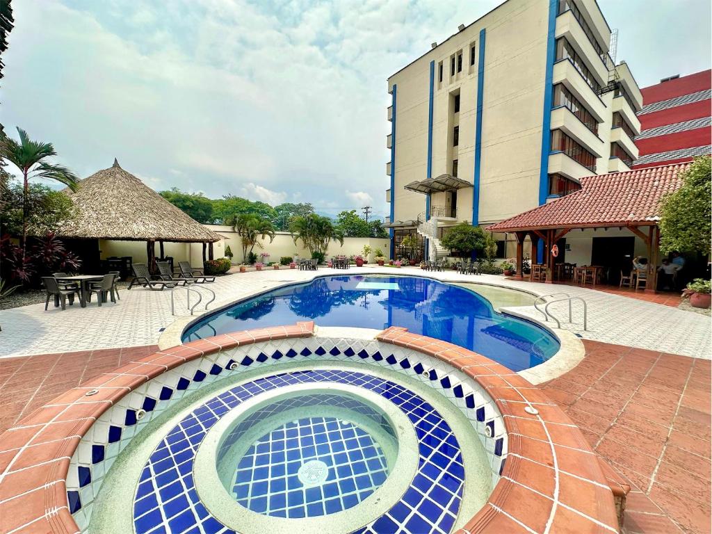 uma piscina num hotel com um edifício ao fundo em Hotel Maria Gloria em Villavicencio