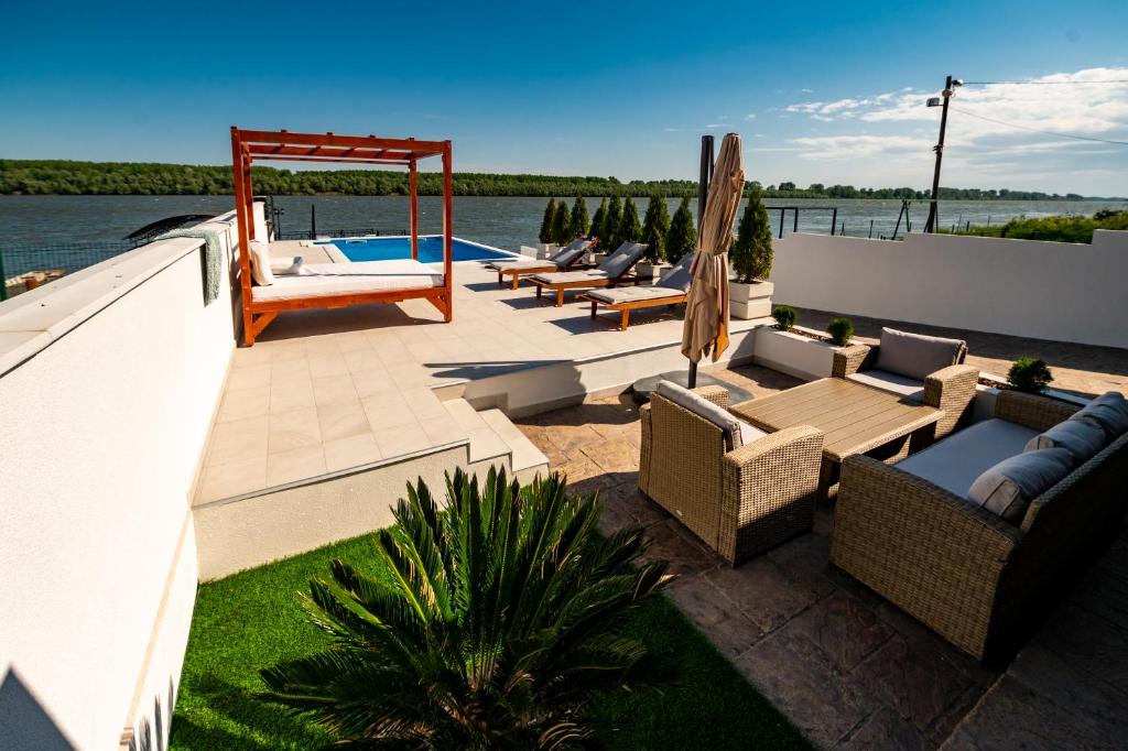 a patio with chairs and a swing and a pool at Harmonija na Dunavu in Smederevo