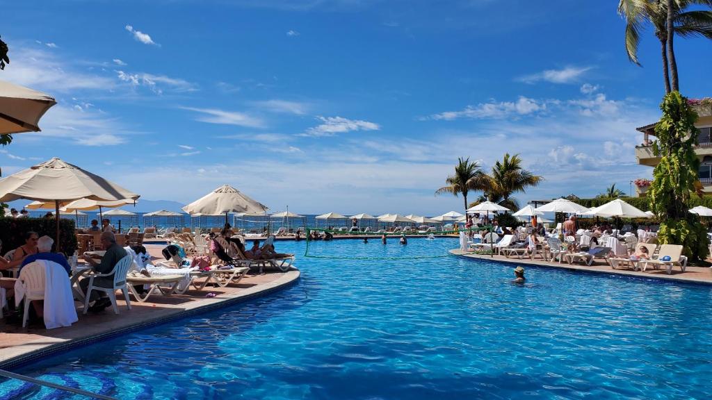 プエルト・バジャルタにあるVelas Vallartaのリゾート内のプールの椅子に座っている人々とプールのプールを利用できます。