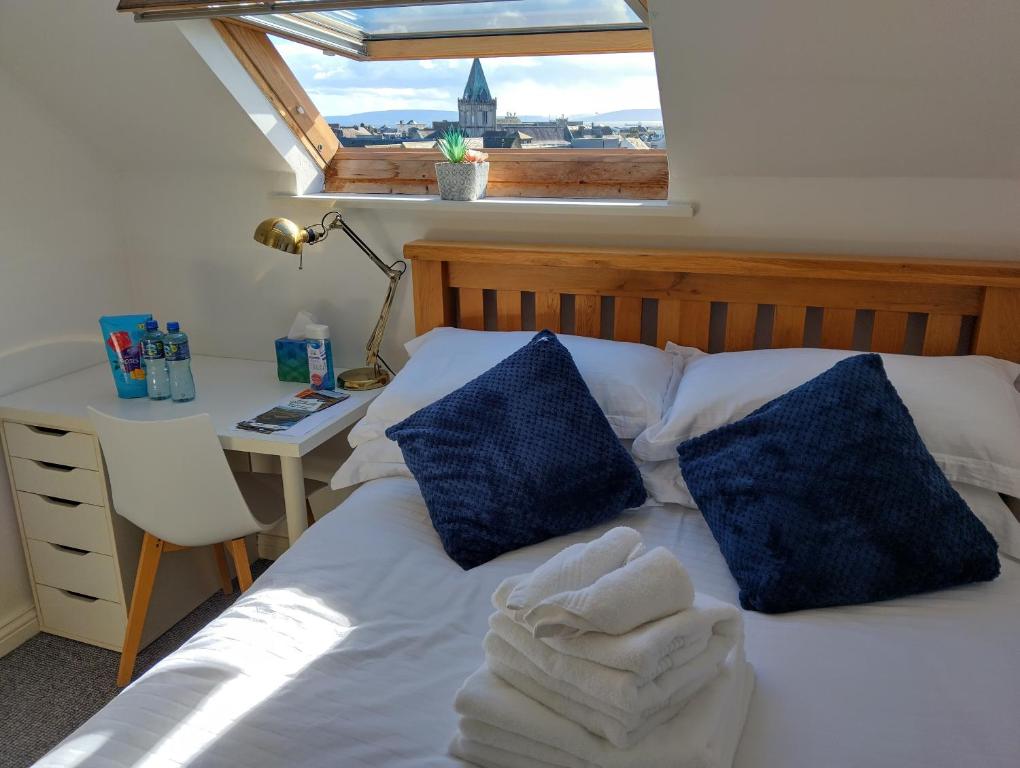 a bed with blue pillows and a desk with a window at Heart of City Centre Stunning View in Galway