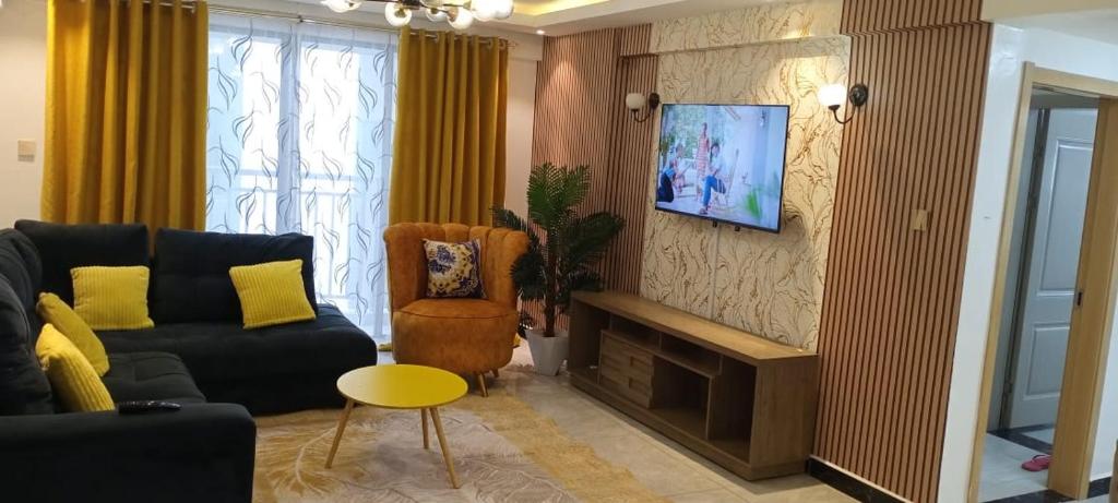 een woonkamer met een bank en een tv aan de muur bij City Haven Accommodation-Two bedroom Apartment in Nairobi