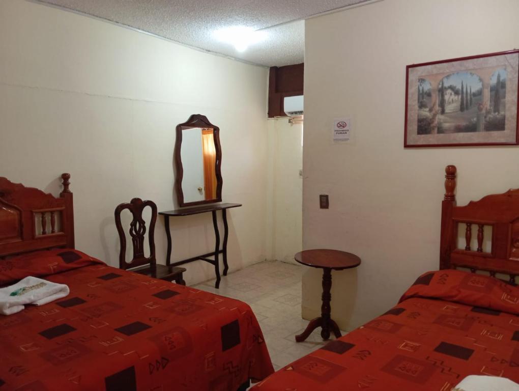 um quarto com 2 camas, uma mesa e um espelho em Hotel Juarez em Minatitlán