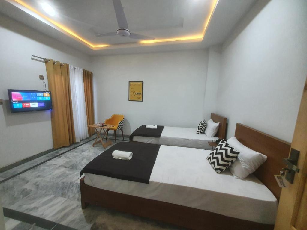 Habitación de hotel con 2 camas y TV en Dastak Hotel, en Islamabad