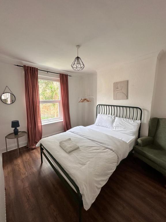 a bedroom with a bed and a chair and a window at Charming, Renovated Residence in Willesden Green in London