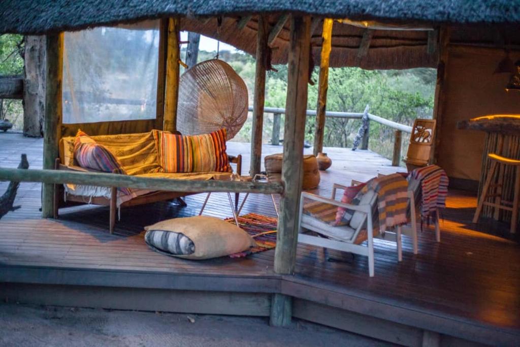 a porch of a house with chairs and a fan at Hyenas Howl Cabins in Muchenje