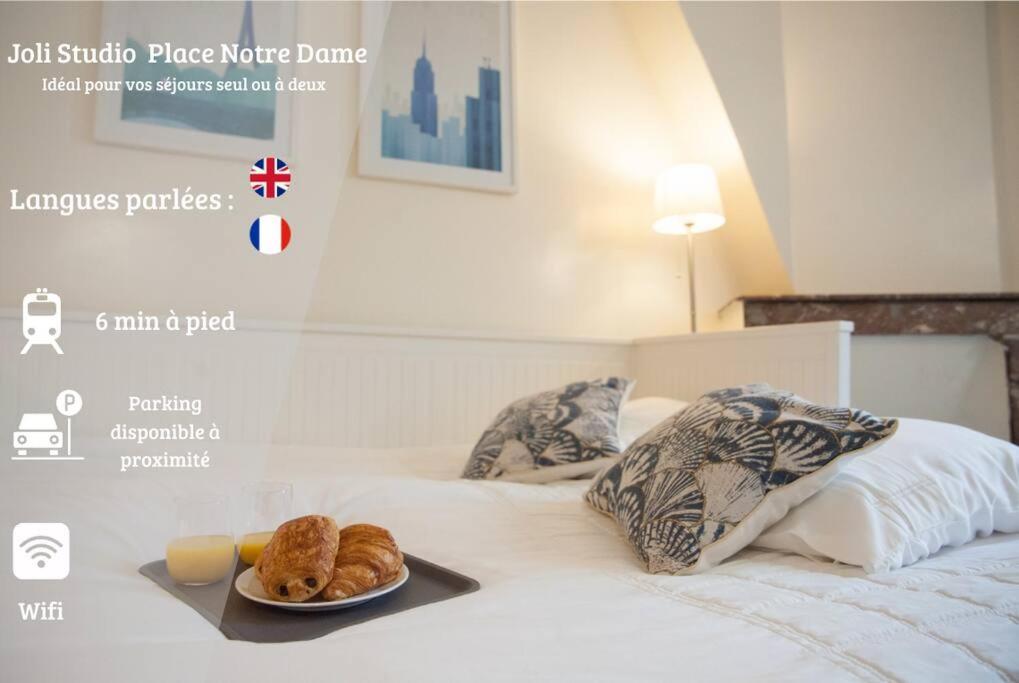 uma cama com uma bandeja de croissants e um prato de pão em Joli Studio Place Notre Dame em Pontoise