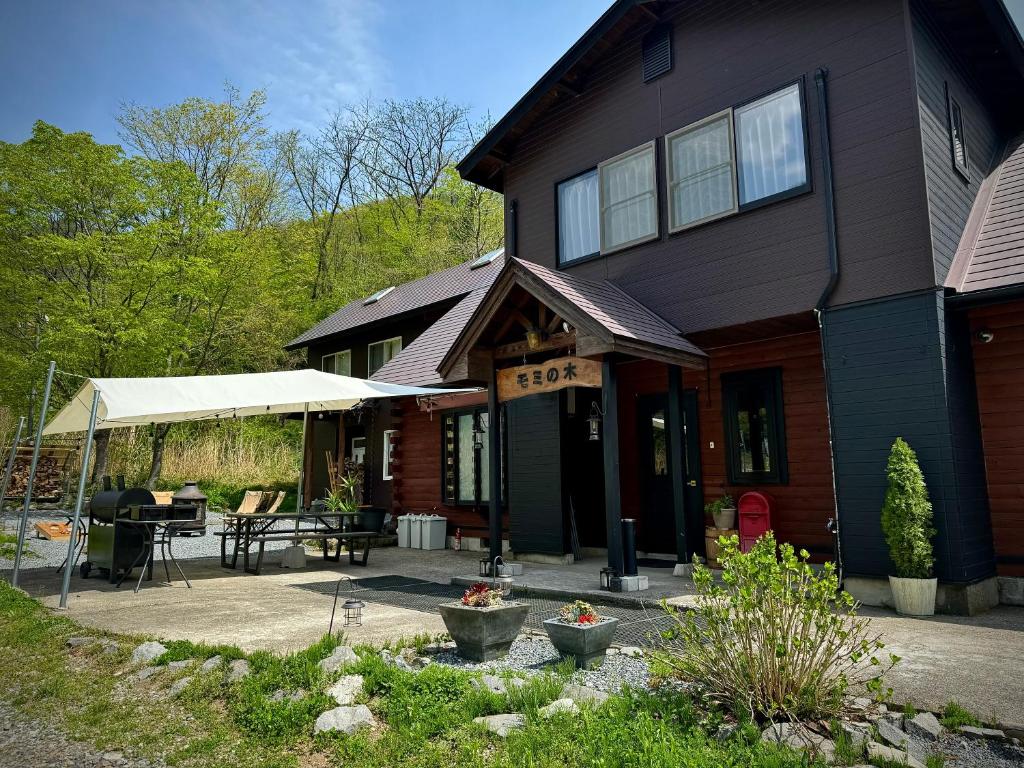 a house with a patio and a table in front of it at Mominoki Lodgeモミの木ロッジ in Minakami