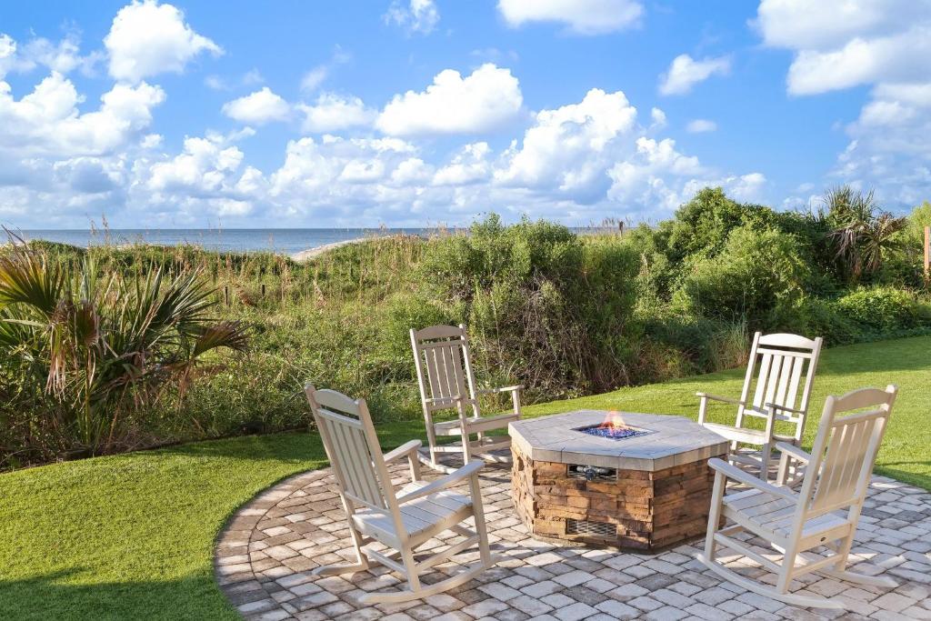 eine Terrasse mit drei Stühlen und einem Tisch mit Kamin in der Unterkunft Club Wyndham Westwinds in Myrtle Beach