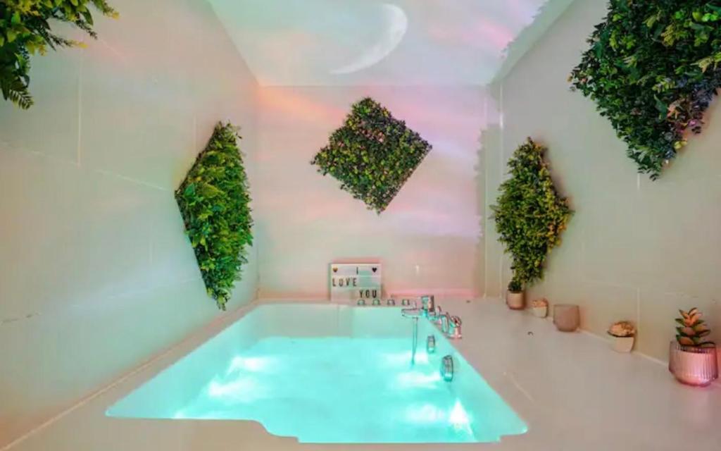 a bathroom with a tub with plants on the wall at Escale Caux Cooning**** Charme et Balneo Etretat in Étretat