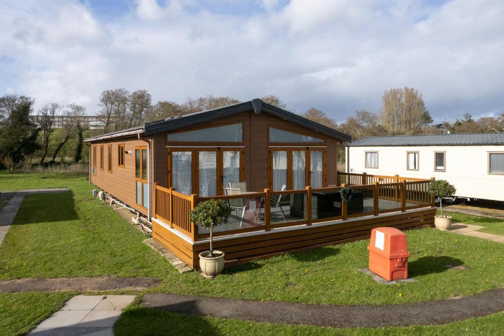 a house with a large deck in a yard at Cormorant - Luxury Lodge Close to the Beach in Tenby