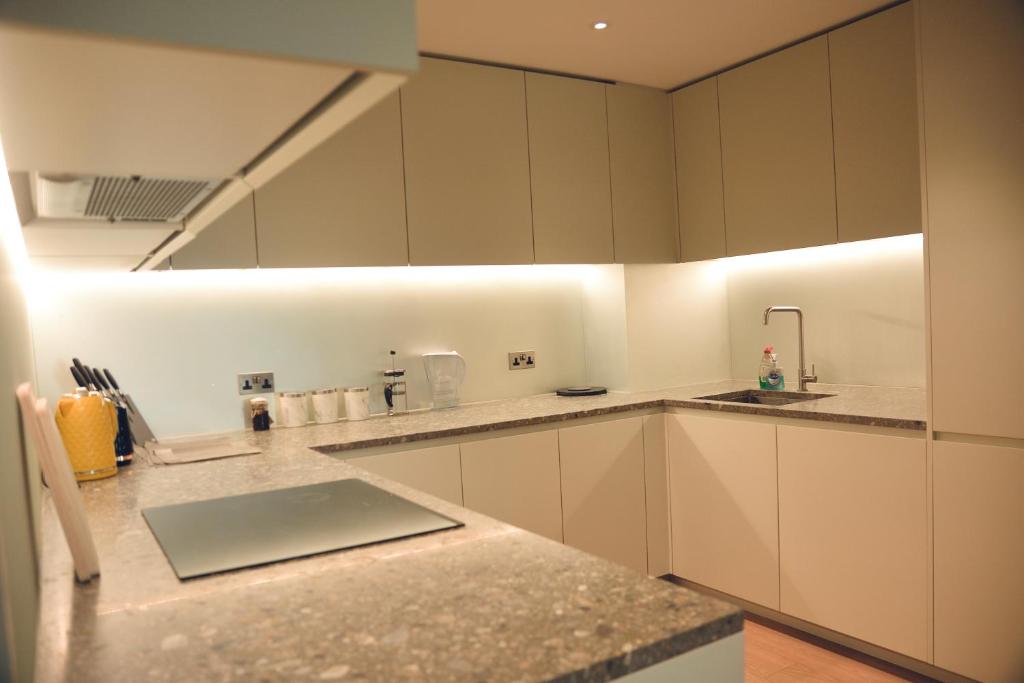 una cocina con armarios blancos y fregadero en O2 Arena 2Bedroom Flat, London 05 en Londres