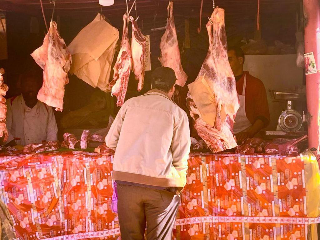 a man standing in front of a market with meat hanging at Luxury tent in the middle of nature 