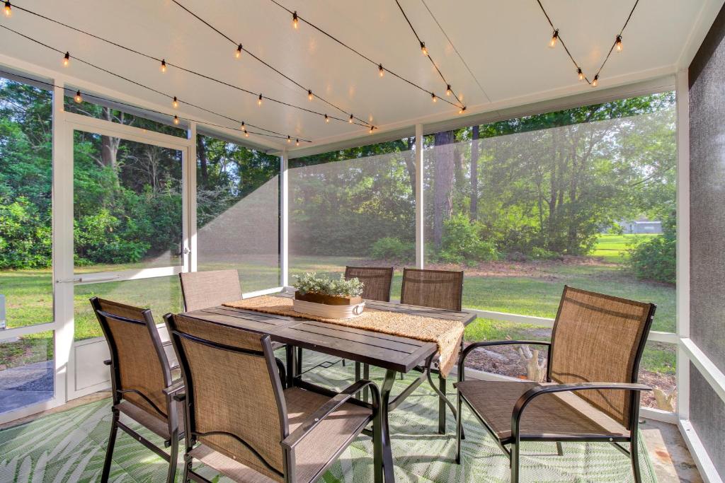 a screened in porch with a table and chairs at Garden City Home with Screened Porch Near Savannah! in Savannah