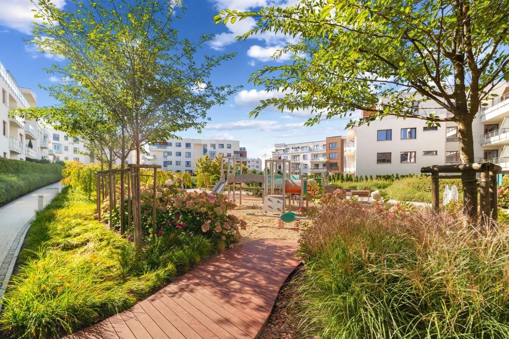 Un jardín con un camino, árboles y edificios. en Altoria Sunset Gdynia, en Gdynia