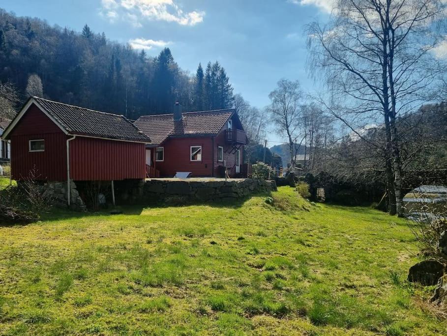 czerwony dom na polu obok podwórza w obiekcie Sjarmerende hus med bade og fiskemuligheter w mieście Flekkefjord