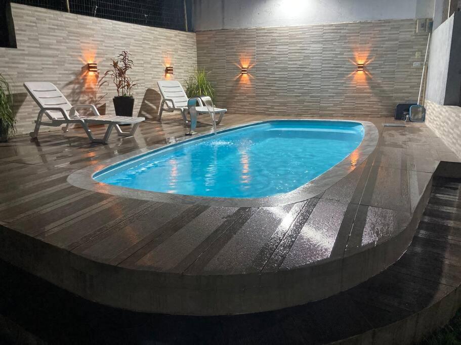 een zwembad in een kamer met stoelen en een tafel bij Praia da Cocanha - Caraguá SP - Área gourmet TOP in Caraguatatuba