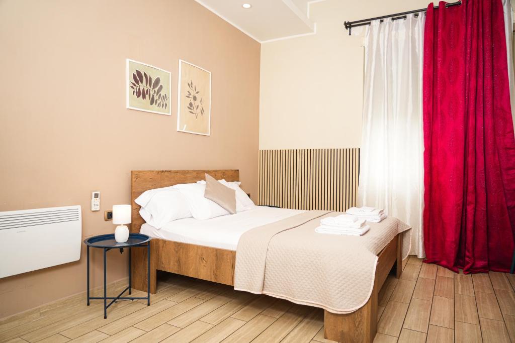 ナポリにあるB＆B メトロポリタンのベッドルーム1室(赤いカーテン付きの大型ベッド1台付)