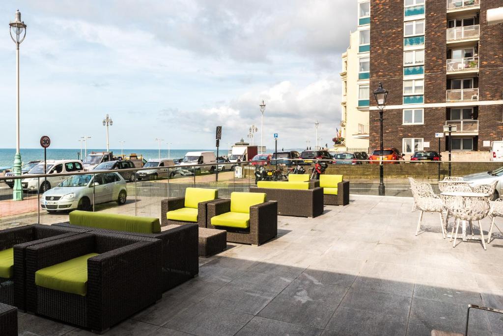 a patio with couches and tables and chairs and the ocean at Holiday Inn Brighton Seafront by IHG in Brighton & Hove