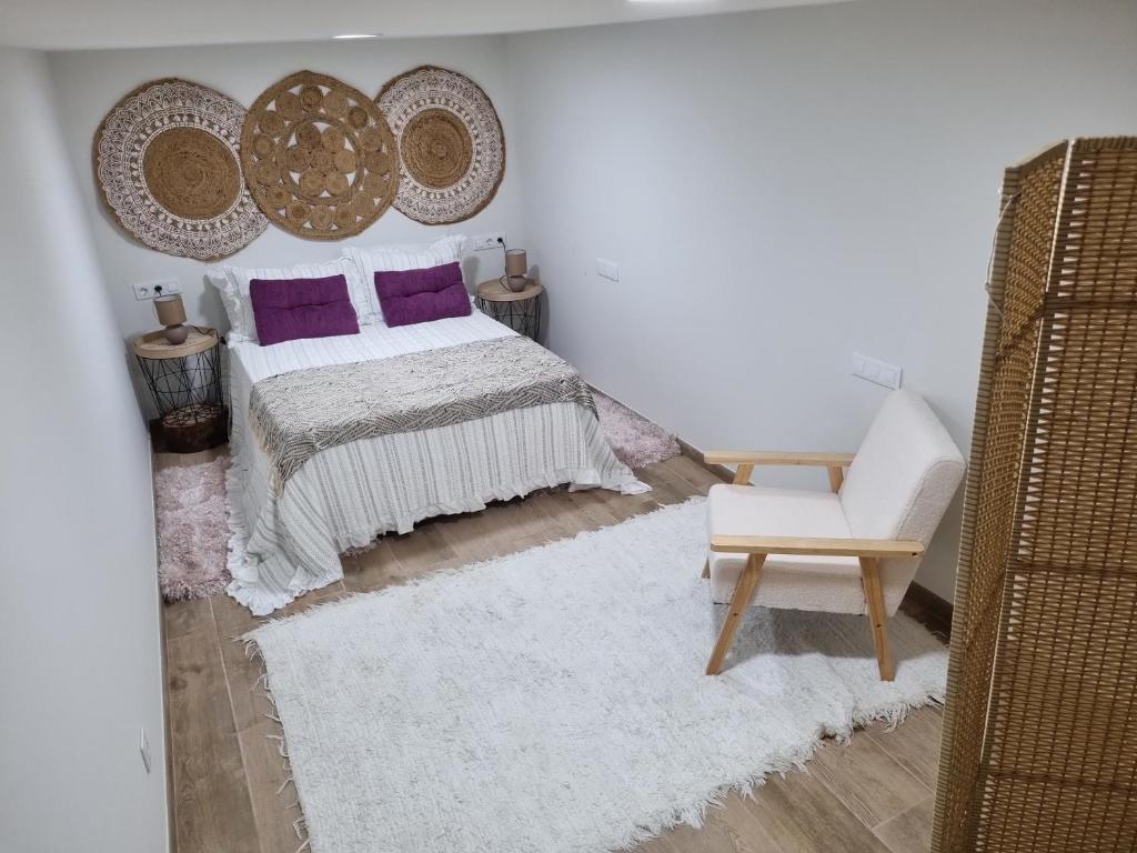 een slaapkamer met een bed met paarse kussens en een stoel bij Casiña Ermi in Porriño