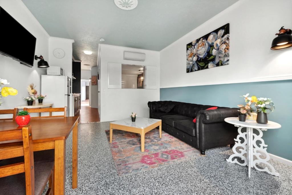 a living room with a black couch and a table at Villa Vaucluse Apartments in Cairns