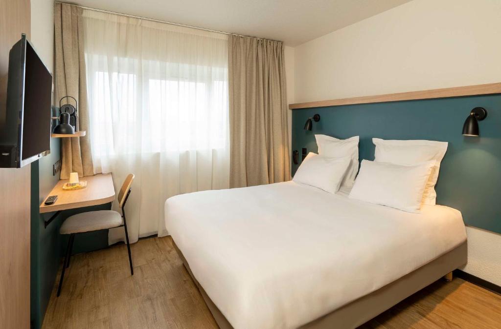 um quarto de hotel com uma grande cama branca e uma secretária em Le Carline, Sure Hotel Collection by Best Western em Caen