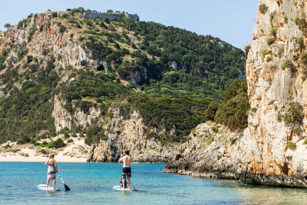 two people on paddle boards in the water near a mountain at Mandarin Oriental, Costa Navarino in Pylos