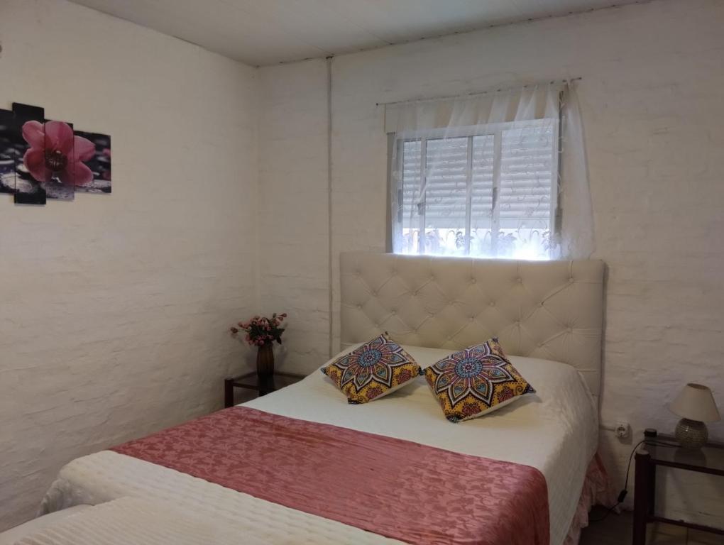 een slaapkamer met een bed met 2 kussens en een raam bij Lugar tranquilo in Colonia del Sacramento