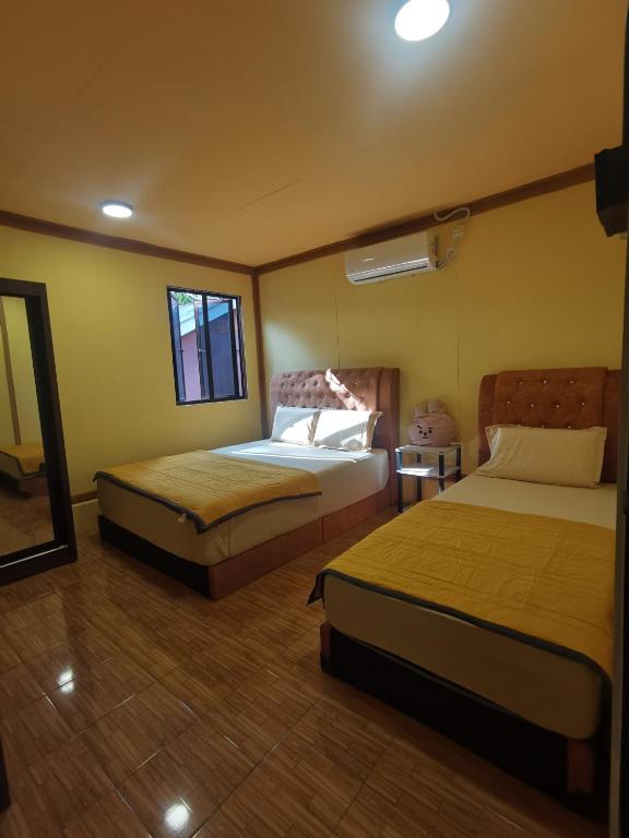 a hotel room with two beds and a mirror at Permata Beach Chalet in Kampong Juara