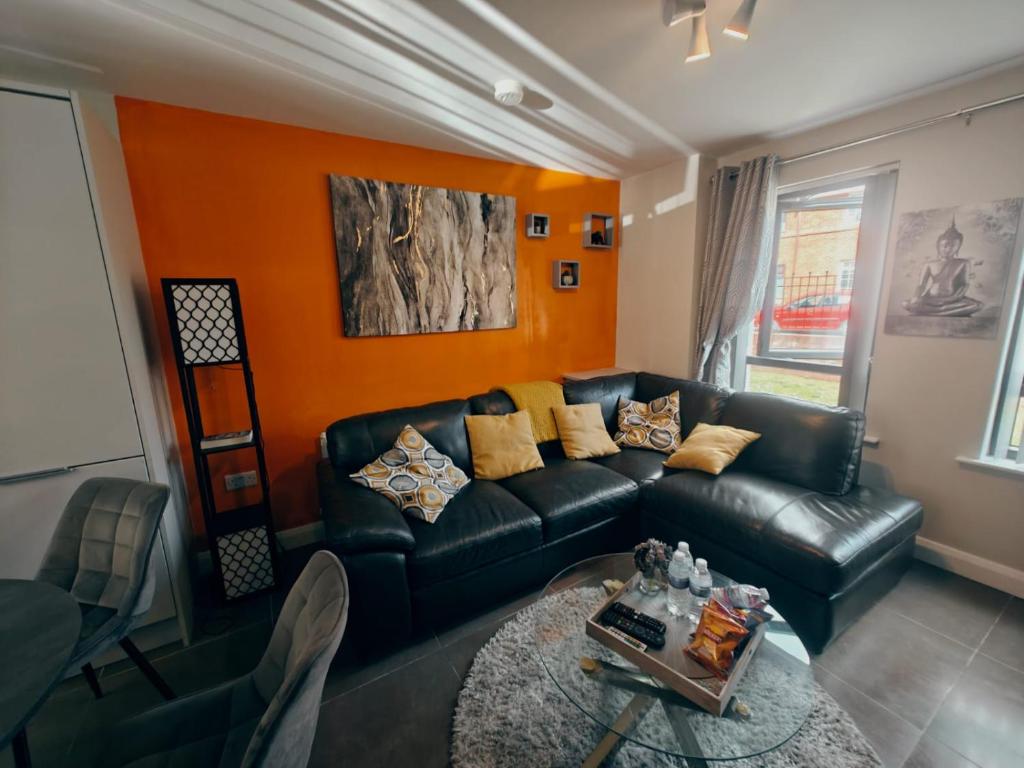 a living room with a black leather couch and a table at Belfast Central 2 Bedroom Luxurious Modern Stay in Belfast
