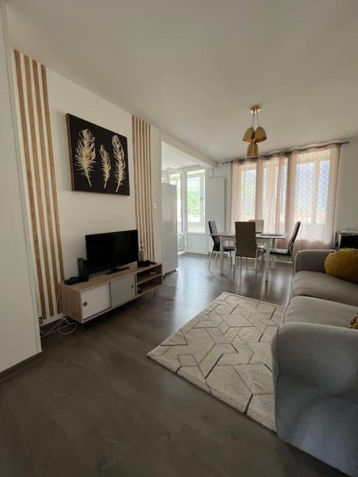 un salon avec un canapé, une télévision et une table dans l'établissement Le grand arc, proche centre ville, à Albertville