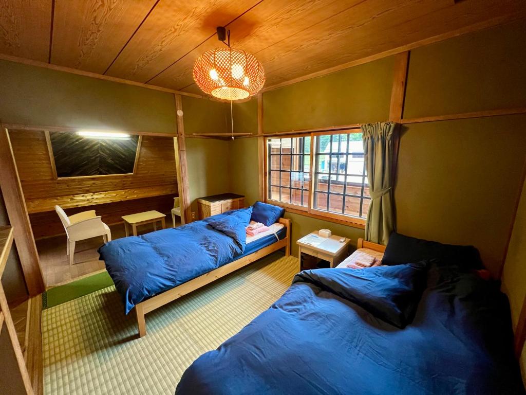 a room with two beds and a table and a window at Little Alaskan Guest House in Hakuba