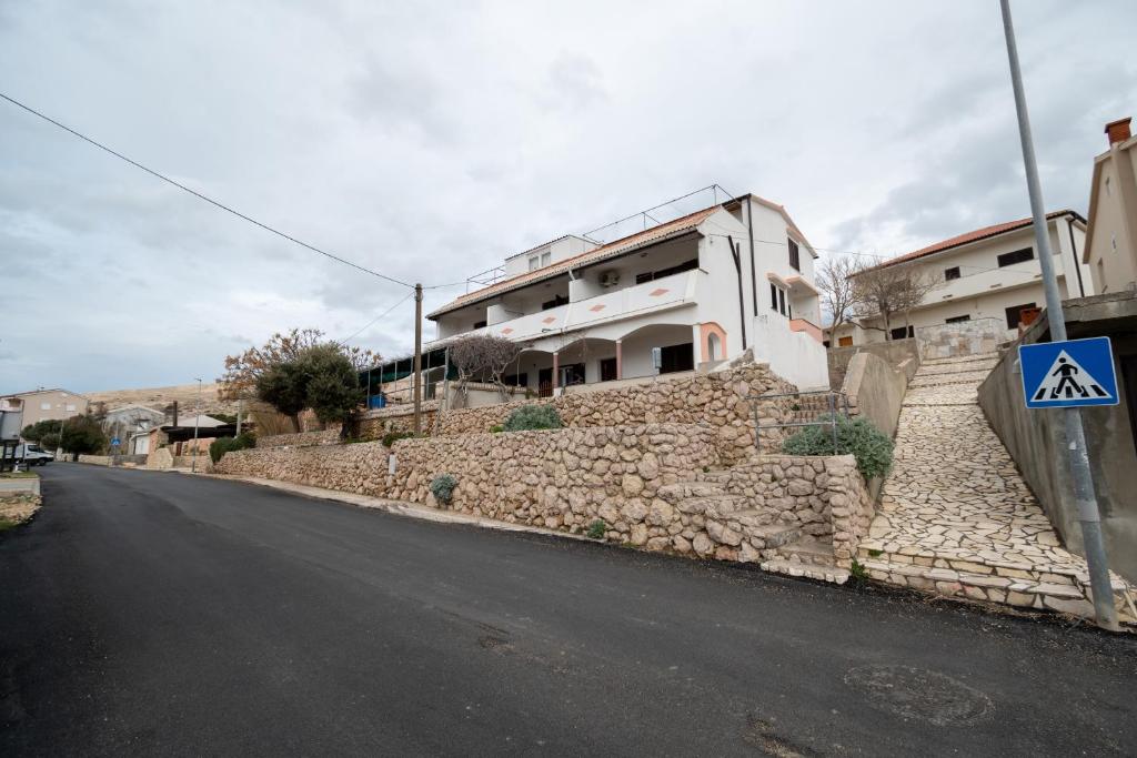 a stone wall next to a building on a street at Apartments and rooms with parking space Zubovici, Pag - 16063 in Zubovići
