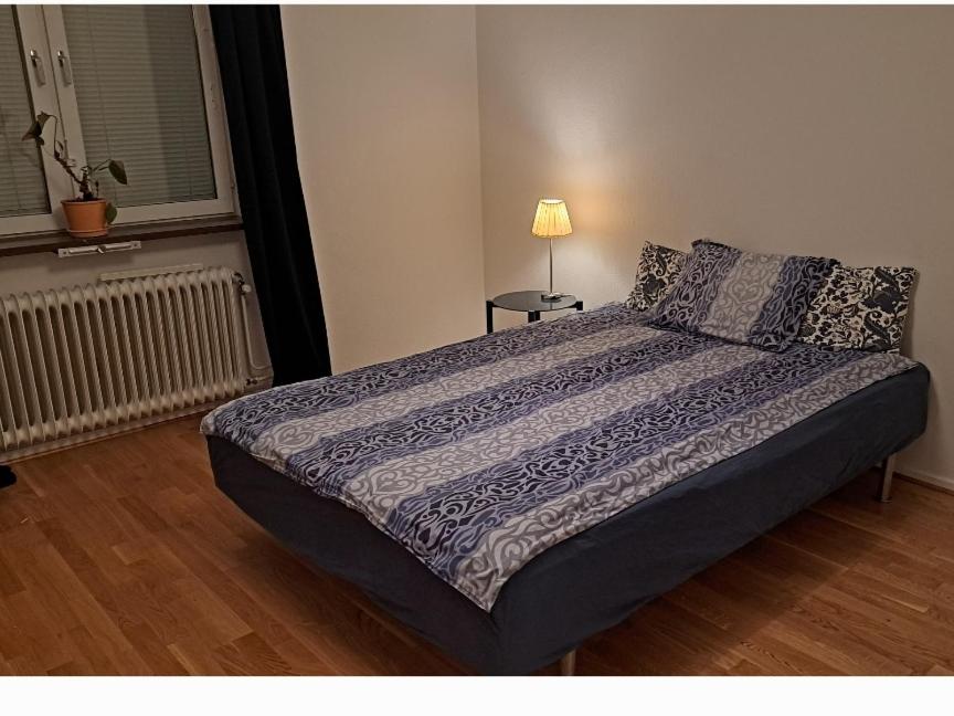 een slaapkamer met een bed en een lamp op een vloer bij Room in apartment in Malmö