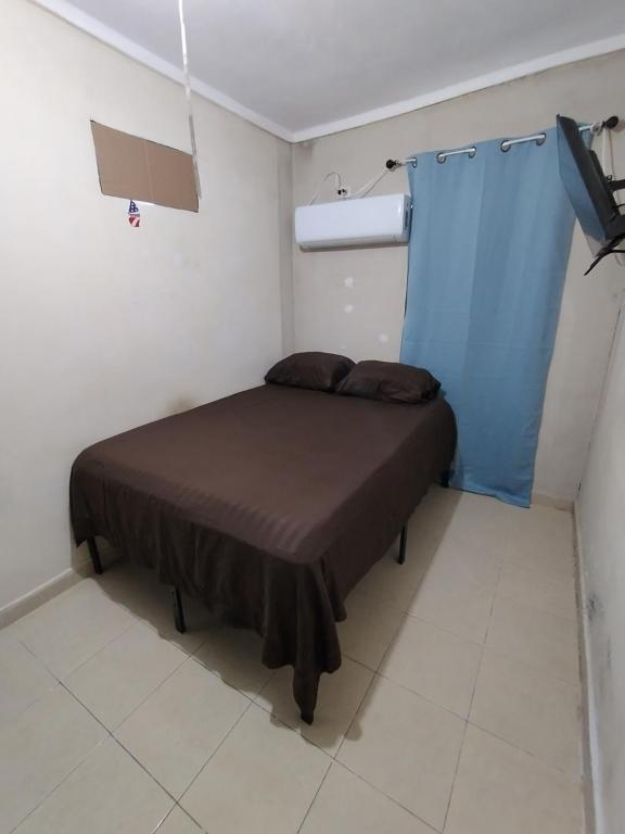 a small bedroom with a bed with a blue curtain at Habitación 2, 1 Cama Matrimonial in Matamoros
