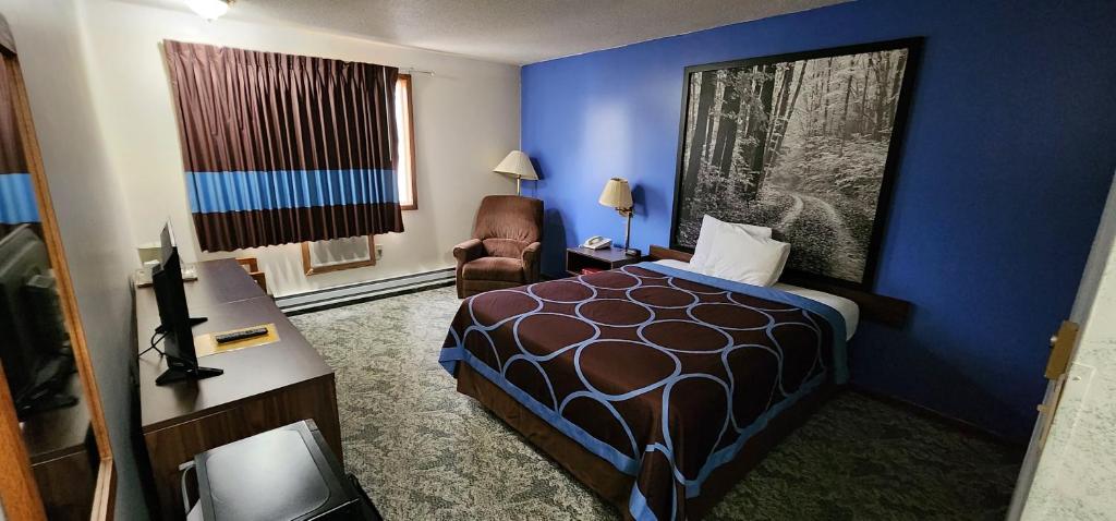 ein Hotelzimmer mit einem Bett und einem Stuhl in der Unterkunft Hotel Iron Mountain Inn & Suites - Stay Express Collection in Iron Mountain