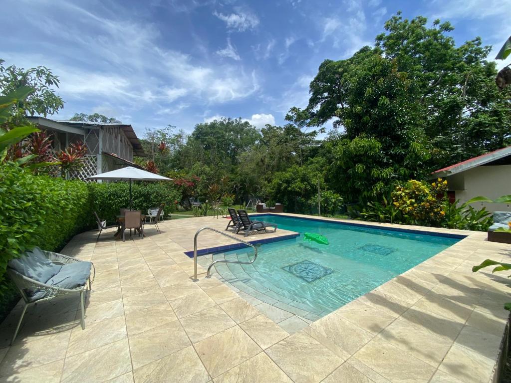 a swimming pool with chairs and a table next to it at Finca Cristal con Piscina Room Blanca con AC in Punta Uva