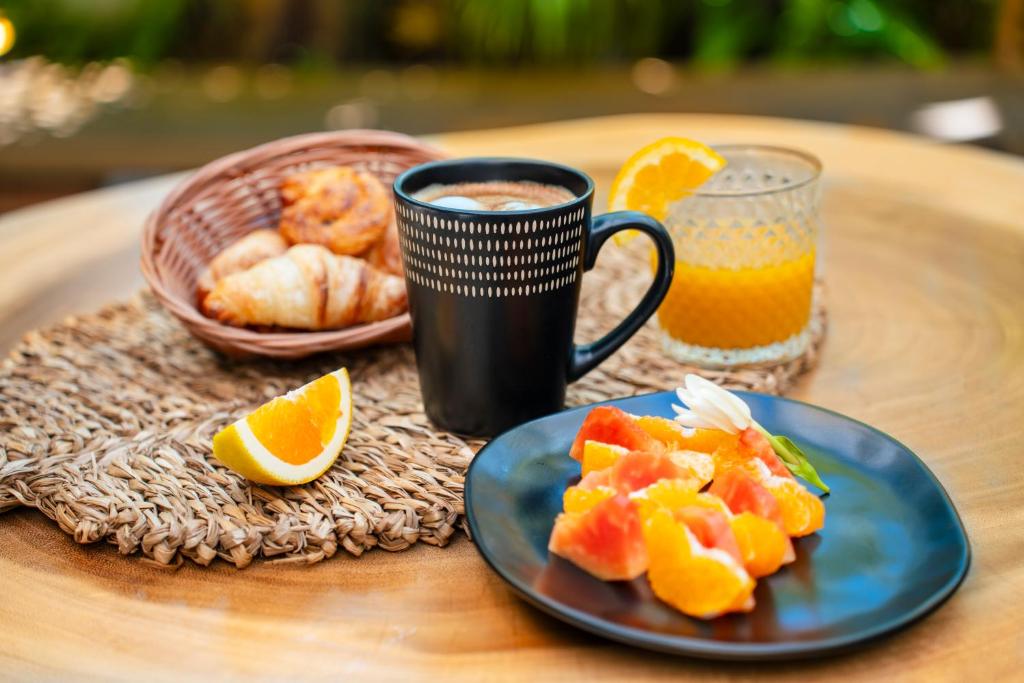 a table with a plate of fruit and a cup of coffee at Polynesian Cabins by Kon Tiki in Papeete