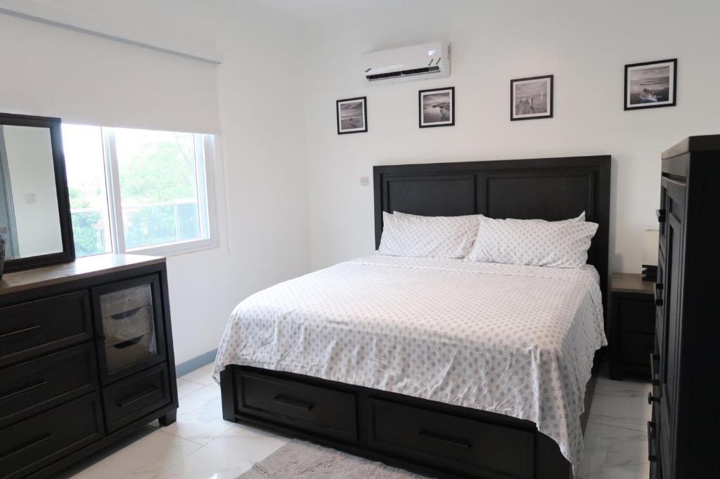 a white bedroom with a bed and a television at Chateau Apartment in New Kingston