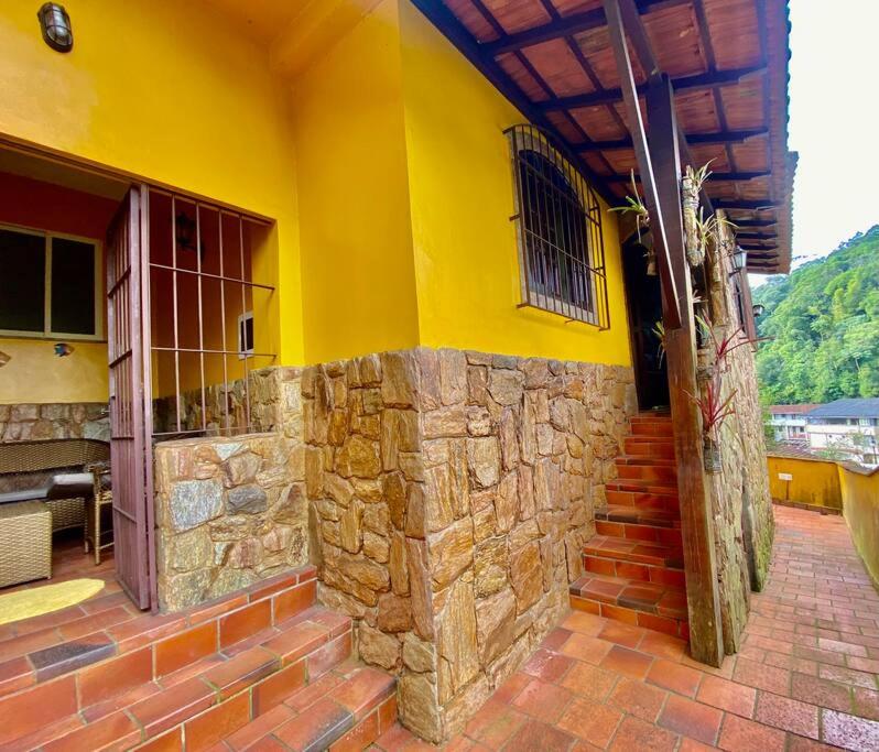 a yellow building with a stone wall and stairs at Casa 86 Quitandinha Petrópolis in Petrópolis