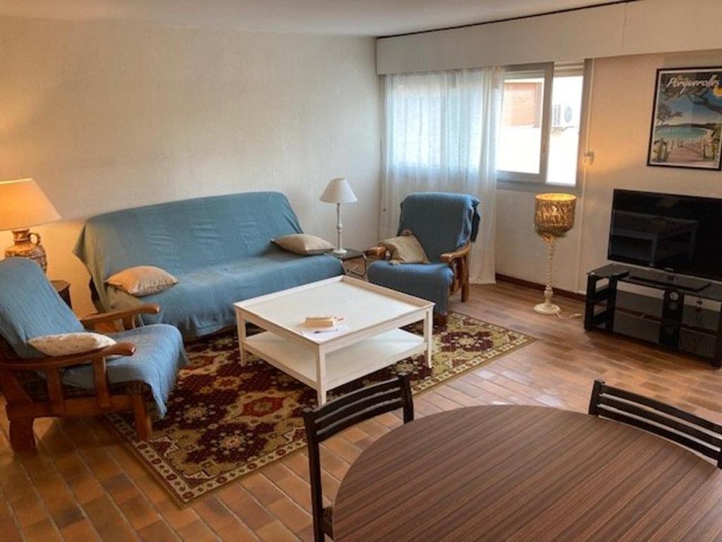 un salon avec un canapé bleu et des chaises dans l'établissement Appartement Climatisé, Traversant avec Parking Privé - Centre Ville Le Lavandou - FR-1-308-193, au Lavandou