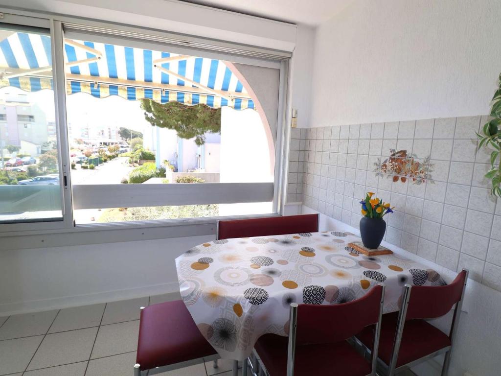 une table et des chaises dans une cuisine avec une fenêtre dans l'établissement Studio cabine climatisé proche plage avec parking privé, piscines et jardins d'enfants - FR-1-307-258, au Grau-du-Roi
