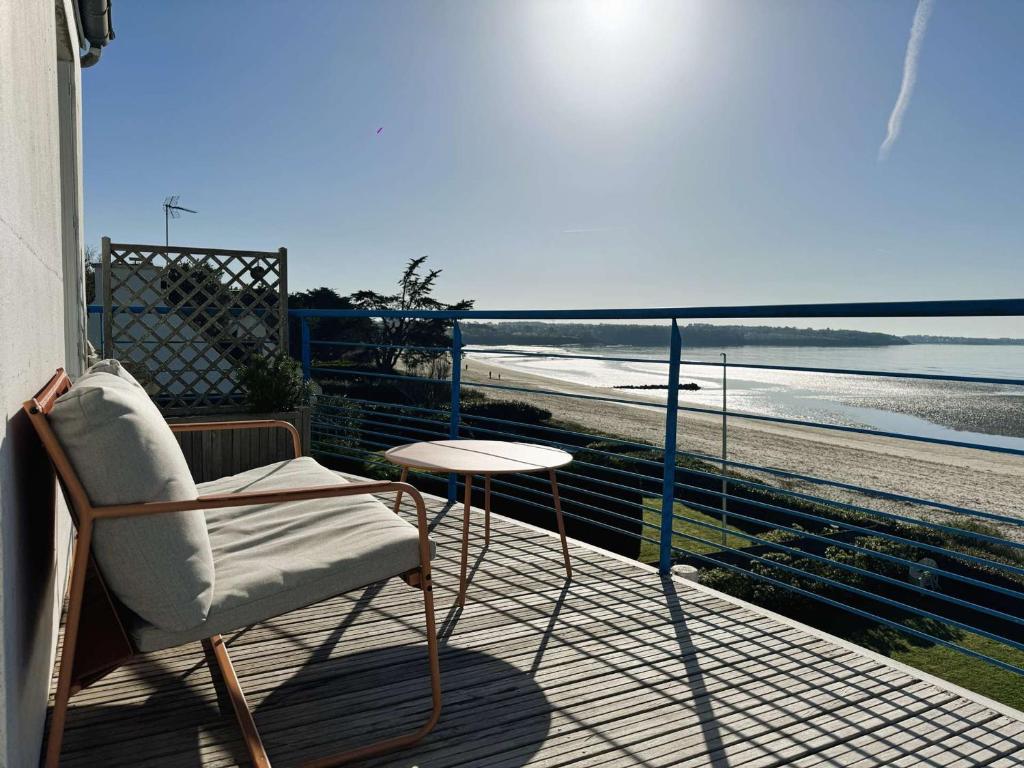 d'une chaise et d'une table sur un balcon avec vue sur la plage. dans l'établissement La Forêt-Fouesnant, appartement rénové pour 2, accès direct plage - FR-1-481-163, à La Forêt-Fouesnant