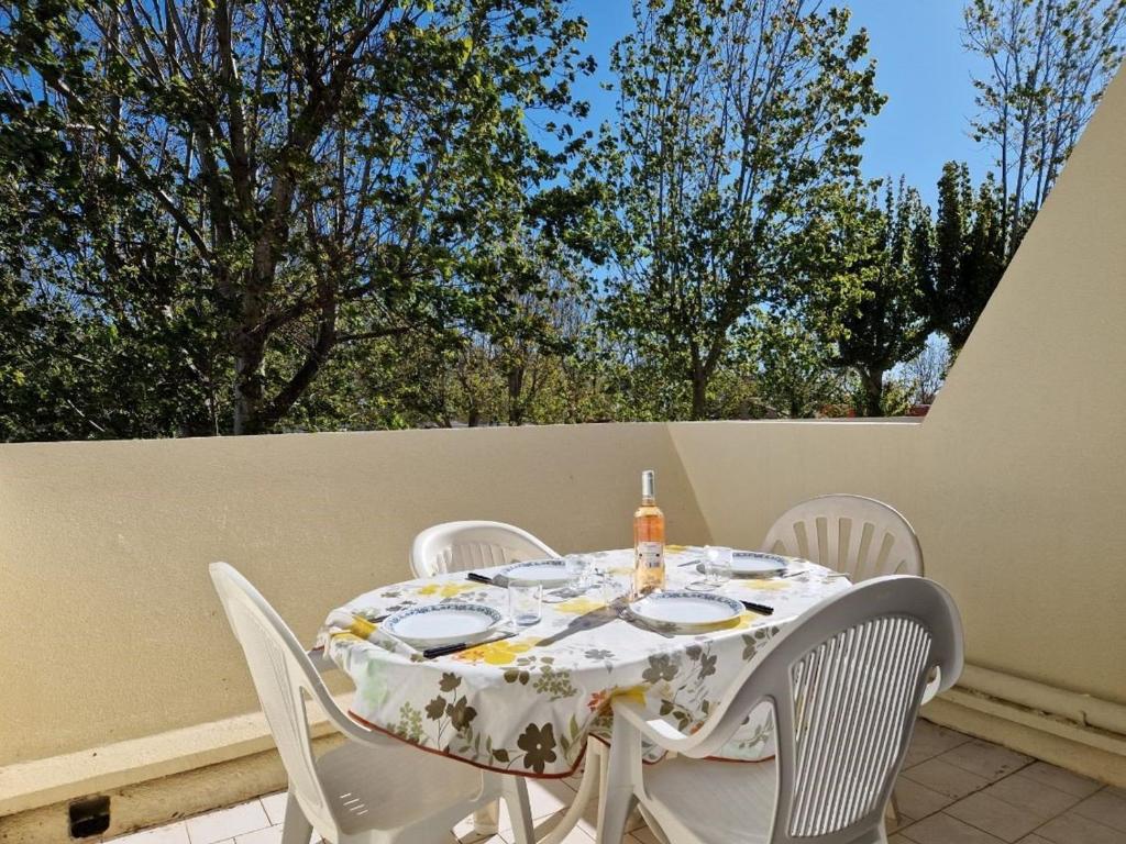 une table et des chaises blanches sur un patio arboré dans l'établissement Appartement T2 avec accès direct plage, terrasse privée et parking - Animaux admis - FR-1-387-205, à Marseillan