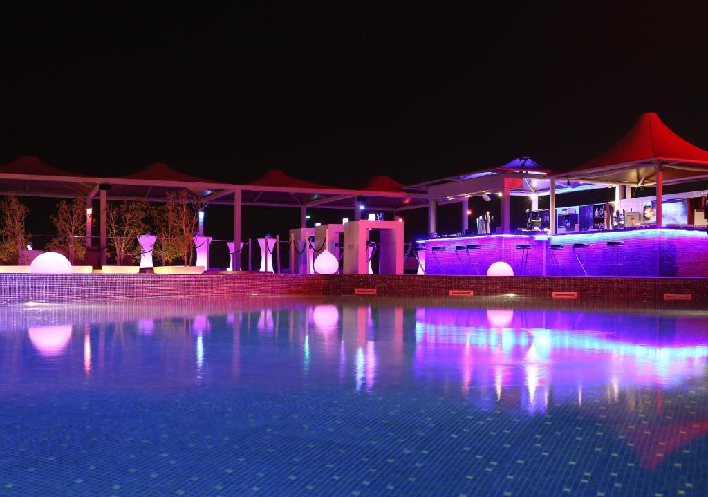 una piscina por la noche con luces moradas en Golden Tulip Muscat, en Mascate