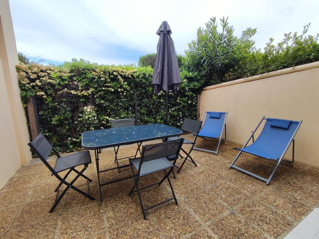 une table, quatre chaises et un parasol sur la terrasse dans l'établissement Studio 4 pers. avec piscine, tennis et parking privé à 500m de la plage, Argelès-sur-Mer - FR-1-776-92, à Argelès-sur-Mer