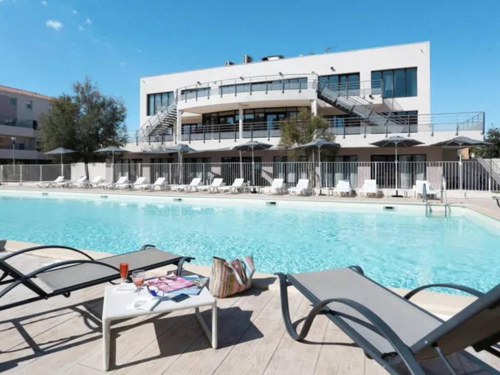 a swimming pool with chairs and a building at Appartement Le Grau-du-Roi, 3 pièces, 6 personnes - FR-1-250-268 in Saint-André-Lachamp